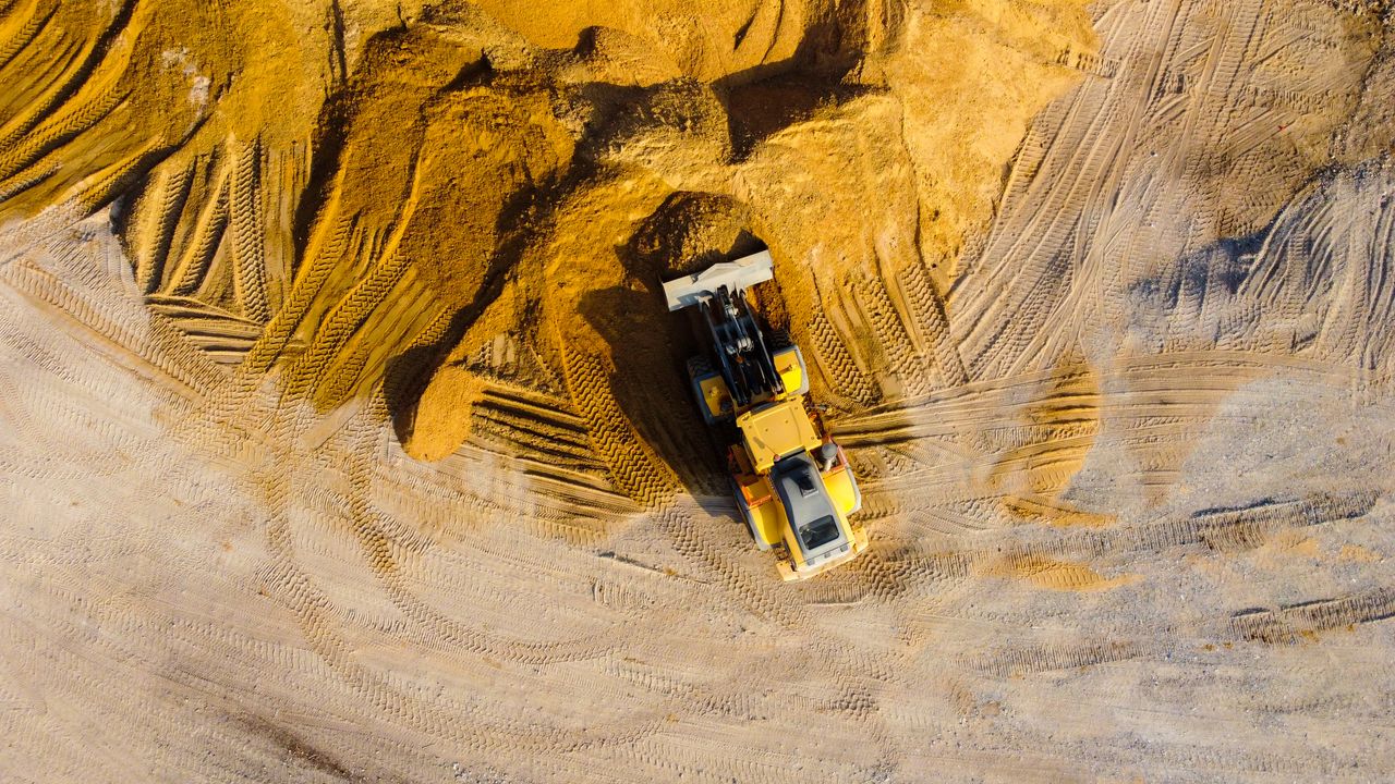 Drone shot of an excavator working on sand mounds at a construction site in Ashdod, Israel.