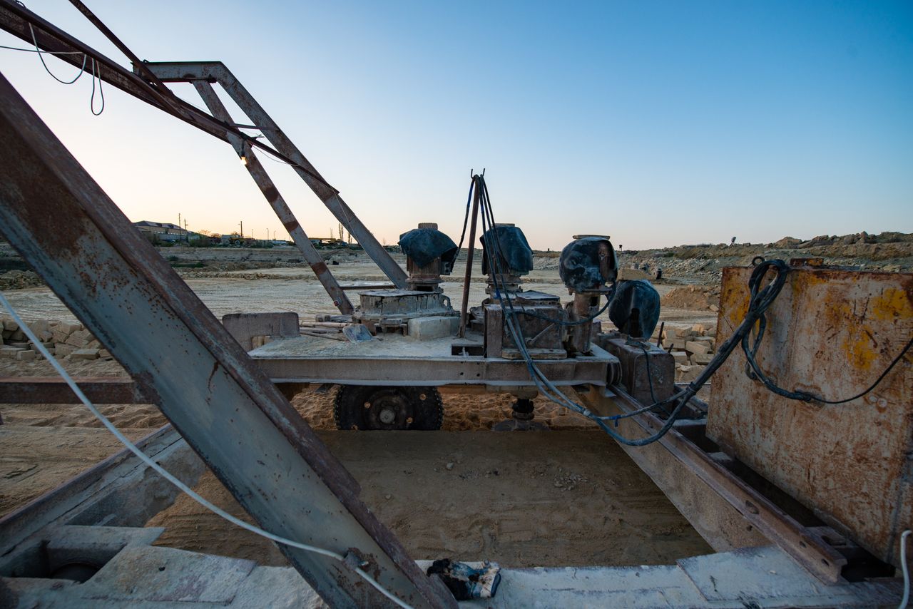 Industrial machinery sitting on sandy construction site under a blue sky, showcasing heavy equipment.